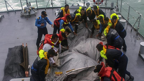 Fotografía facilitada por la Armada de Malasia que muestra a miembros del buque de la Armada Malasia "Lekir" recuperando una pieza del Airbus 320-200 de AirAsia siniestrado el domingo en el mar de Java con 162 personas a bordo, frente a la 