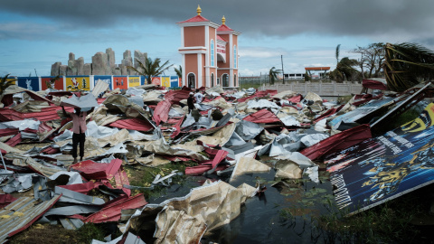 Personas recolectan láminas de metal de un supermercado dañado para reconstruir sus casas destruidas por el ciclón Idai en Beira, Mozambique | AFP/ Yasuyoshi Chiba