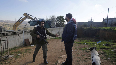 Un policía israelí habla con un palestino durante la destrucción de una empalizada en Hebrón. REUTERS/Mussa Qawasma