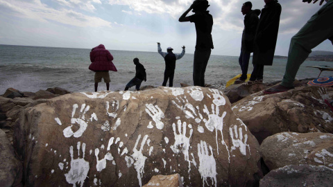 Un grupo de emigrantes sudaneses y eritreos cerca de una roca con impresiones blancas de manos en el cruce fronterizo de San Ludovic, en el mar Mediterráneo entre Vintimille, Italia y Mentón, Francia. REUTERS / Eric Gaillard