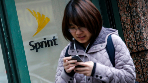 Una mujer maneja su móvil junto a una tienda de Sprint en Nueva York. REUTERS/Brendan McDermid