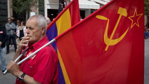 Un veterano manifestante con las banderas republicana y del Partido Comunista espera fumando la salida de la manifestación del Primero de Mayo en Sevilla , donde miles de personas se han dado cita para reivindicar la igualdad de género, el 