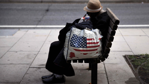 Una mujer sin hogar descansa en un banco a pocos metros de la Casa Blanca en Washington. CARLOS BARRIA (AFP)