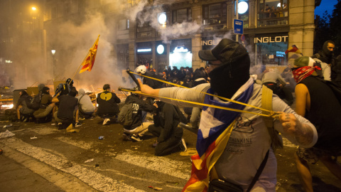 Jóvenes manifestantes se atrincheran en el centro de una calle de Barcelona y hacen frente a los antidisturbios. GUILLEM SANS