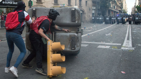 Dos encapuchados empiezan a montar una barricada, con un contenedor y un semáforo arrancado, en la Vía Layetana de Barcelona. GUILLEM SANS