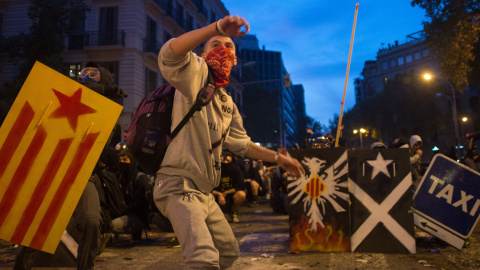 Jóvenes con escudos de metal y los rostros cubiertos empiezan a retroceder ante el avance de los antidisturbios en el centro de Barcelona. GUILLEM SANS