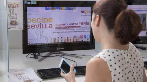 Una chica votando en la plataforma de "Decide Sevilla" la duración de la Feria de Abril/EFE