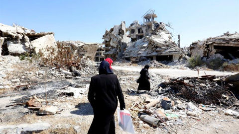 Mujeres sirias caminan entre las ruinas de la ciudad Homs, Siria. EFE/Youssef Badawi