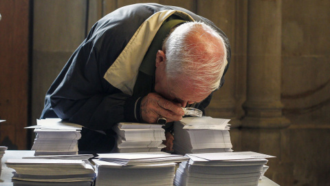 Una persoma observa con una lupa las papeletas de los diferentes partidos que concurren a las elecciones al Parlament. EFE/ Quique García