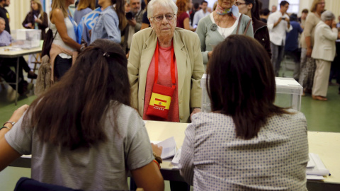 Una mujer con un bolso con los colores de la bandera española deposita su voto en un colegio electoral en Barcelona. REUTERS/Andrea Comas