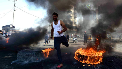 Un manifestante corre entre rueda de coche ardiendo durante una manifestación en la plaza de Khillani en Bagdad, Irak.EFE/ Murtaja Lateef