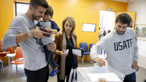 El jugador del FC Barcelona Gerard Pique, con su hijo Milan en brazos, vota en su colegio electoral en Sant Just Desvern, en Barcelona. REUTERS/Albert Gea