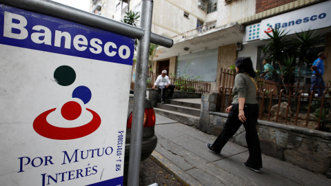 Una mujer camina junto a una sucursal del banco Banesco en Caracas. REUTERS/Carlos Garcia Rawlins