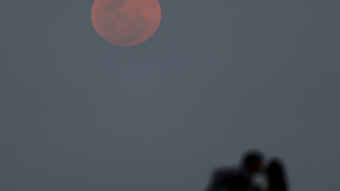 Una pareja se besa mientras observa la superluna desde Río de la Plata, en Buenos Aires.  REUTERS/Enrique Marcarian