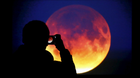 Un hombre fotografía la superluna roja en Varsovia (Polonia). REUTERS/Kacper Pempel