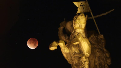 Fotografía de un eclipse total de luna visto junto a una escultura del apóstol Santiago a caballo en la madrugada de hoy, lunes 28 de septiembre de 2015, cerca al ayuntamiento de Santiago de Compostela (España). EFE/Lavandeira jr