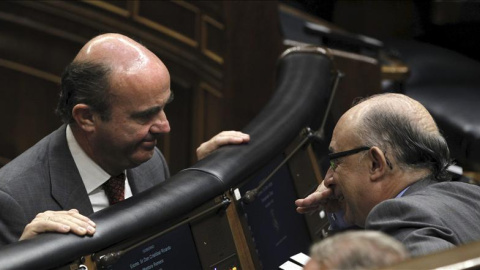 El ministro de Economía, Luis de Guindos, conversa con el ministro de Hacienda, Cristóbal Montoro, en el Congreso de los Diputados. EFE