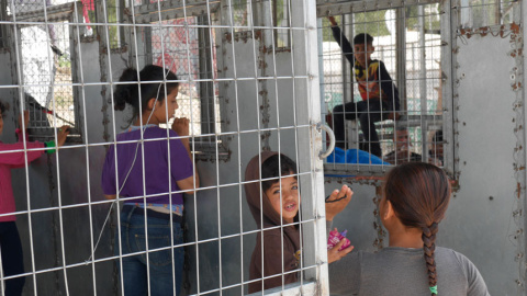 Niños en la fila de reparto de comidas, enrejada, como otro punto caliente conflictivo entre los internos por la escasez de alimentos. / M.I