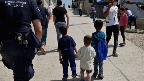 Tres niños pequeños solos de la mano recorren el campamento entre adultos desconocidos y policías. / M.I