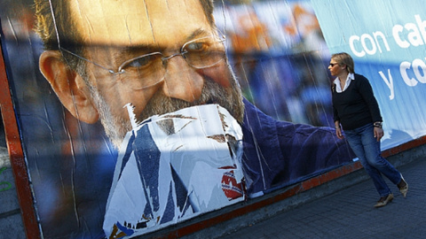 Una mujer camina ante una valla electoral con la imagen de Mariano Rajoy. / FOTO: MANUEL MARRAS