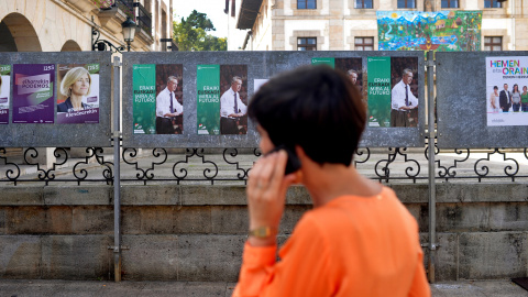 Una mujer habla por su móvil junto a varios carteles electorales en la localidad de Guernica. REUTERS/Vincent West