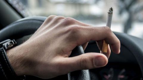 Una persona fumando dentro de un coche.