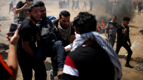 Varios palestinos trasladan a un herido en las protestas en Gaza contra la embajada de EEUU en Jerusalén. - REUTERS