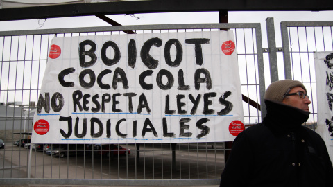 Un empleado de Coca-Cola junto a una pancarta que pide que la empresa acate la sentencia judicial. -JAIRO VARGAS