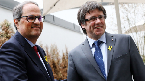 El recentment escollit President de la Generalitat de Catalunya, Quim Torra, es dona la mà amb el President cessat, Carles Puigdemont.