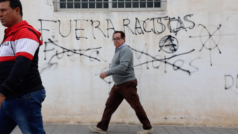 Vecinos de Torre-Pacheco (Murcia) caminan frente a unas pintadas a favor y en contra de la extremada derecha, que ha arrasado en las elecciones generales en la localidad. ENTREFRONTERAS