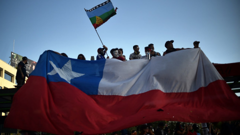 12/11/2019 - Manifestantes sostienen la bandera de Chile y la Mapuche. / AFP - RODRIGO ARANGUA