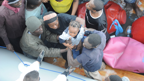 Un militar español recoge a un menor desde la lancha neumática que la tripulación de la fragata 'Reina Sofía' utiliza para acercarse a las embarcaciones de los inmigrantes. Armada Española