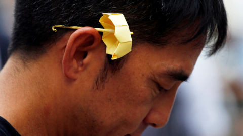 Un hombre con un paraguas de origami amarillo en la oreja, símbolo del movimiento de desobediencia civil 'Occupy Central', participa en el segundo aniversario del movimiento frente a la sede del gobierno en Hong Kong. REUTERS/Bobby Yip