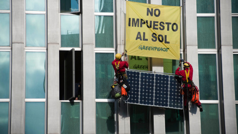 Activistas de Greenpeace subiendo una placa solar por la fachada del Ministerio.