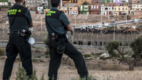 Dos agentes de la Guardia Civil vigilan la frontera de Melilla ante el intento de un grupo de personas de saltarla. AFP