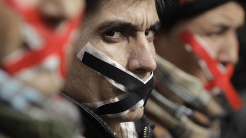 Inmigrantes y solicitantes de asilo, con la boca cubierta con cinta adhesiva, en una manifestación en el centro de Atenas (1 de febrero 2011). REUTERS / John Kolesidis