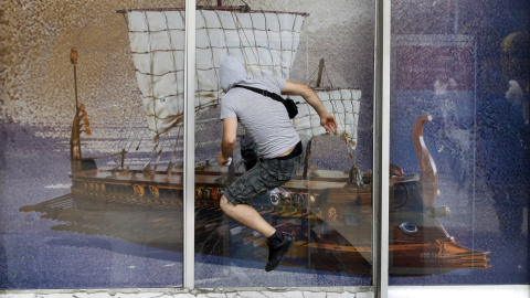 Un manifestante se lanza contra el cristal de un escaparate que muestra una imagen de una antigua galera griega, durante las protestas contra las medidas de austeridad (28 de junio 2011) REUTERS / Yorgos Karahalis