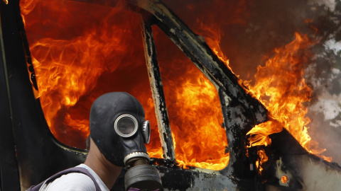 Un manifestante con máscara antigas junto a una furgoneta ardiendo durante las violentas protestas contra las medidas de austeridad en Atenas (28 de junio 2011). REUTERS / Yannis Behrakis