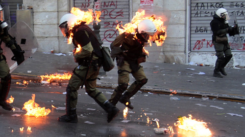 El fuego de unos cócteles molotov alcanza a unos agentes de policía en unos enfrentamientos con manifestantes cerca de la sede del Parlamento en la Plaza Syntagma de Atenas (20 de octubre 2011). REUTERS / Yannis Behrakis