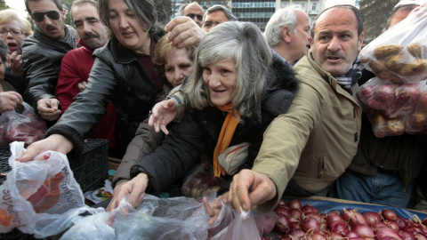 Un grupo de personas trata de recibir gratis cebollas y otras verduras ofrecidas por los agricultores en la plaza Syntagma (25 de enero 2012). REUTERS / Yannis Behrakis