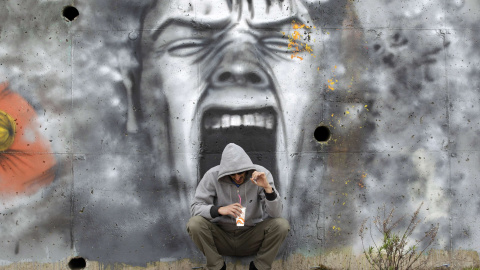 Un hombre bebe café frente a un mural cerca de la ciudad costera de Kalamatta, en la zona de Mesenia de Grecia (23 de marzo 2012). REUTERS / Cathal McNaughton