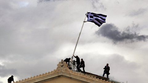 Empleados del Parlamento griego levanta el mástil de una bandera helena (18 de abril 2012). REUTERS / Yannis Behrakis