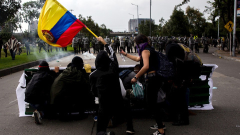 21/11/2019.- Un grupo de jóvenes se cubre frente a miembros de la Policía durante una manifestación en Bogotá (Colombia). / EFE - JUAN ZARAMA