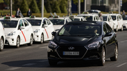 Un coche VTC pasando junto a una hilera de taxis en el centro de Madrid. / Europa Press