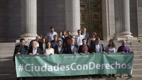 Miembros de Unidos Podemos y representantes de los llamados ayuntamientos "del cambio" posan  a las puertas del Congreso de los Diputados tras presentar una proposición para derogar la ley de Racionalización y Sostenibilidad de la Administr