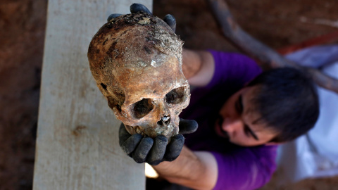 Un arqueólogo de la ARMH-Valladolid sostiene el cráneo de un asesinado por el bando franquista durante la Guerra Civil, en Valladolid.- REUTERS / JUAN MEDINA