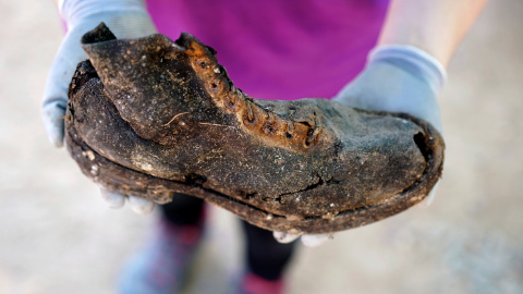 Un miembro de la Asociación por la Recuperación de la Memoria Histórica de Valladolid muestra el zapato de uno de los represaliados por el franquismo exhumados de una fosa junto al cementerio de El Carmen, en Valladolid.- REUTERS / JUAN MED