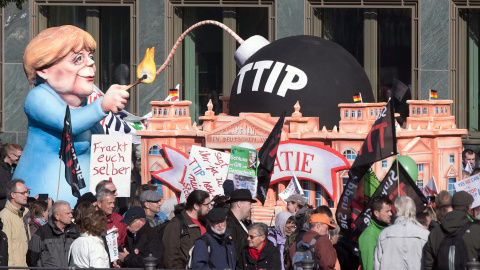 Un muñeco que representa a la canciller alemana, Angela Merkel, encendiendo 'la bomba TTIP', en la manifestación de Berlín contra el acuerdo comercial que negocia la UE con EEUU. EFE / EPA / JOERG CARSTENSEN