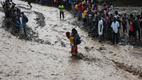 Personas intentan cruzar el río La Digue, debido al derrumbe del único puente que conecta con el sur, tras el paso del huracán Matthew en Haití. EFE