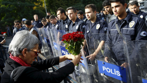 Una manifestante muestra un ramo de flores en la barricada policial deslpegada frente a la concentración en recuerdo de las víctimas del doble atentado suicida en Ankara. REUTERS/Umit Bektas